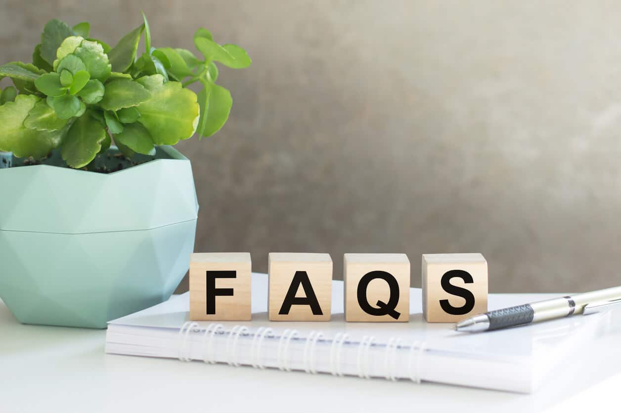 The acronym 'FAQs' spelled out in wooden blocks on a notebook, ready to answer common queries related to salon online booking and salon appointment software, ensuring customer support and service clarity.